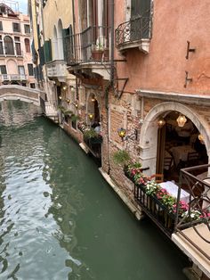 a narrow canal runs between two buildings with flowers on the balconies in venice, italy