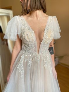 the back of a woman's wedding dress with sheer tulle and beading