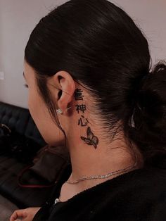 a woman with a butterfly tattoo on her neck and behind her ear is a couch