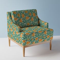 a green and orange patterned chair on a white floor with blue wall in the background