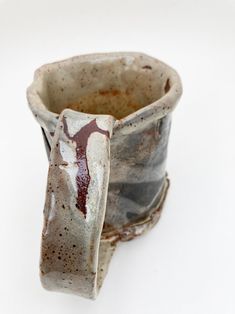 a ceramic cup sitting on top of a white table next to a black and brown object