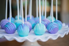 blue and purple cake pops on a white platter with toothpicks in them