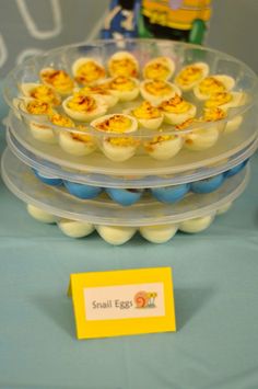 an egg tray with small eggs in it on a blue table cloth next to a yellow sign