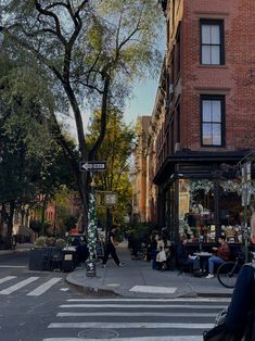 people are sitting at tables on the sidewalk in front of an old brick building with many windows