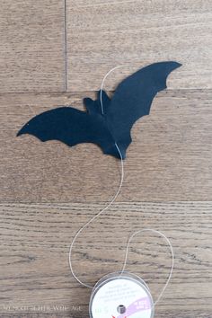 a spool of thread with a bat cut out of it on top of a wooden floor