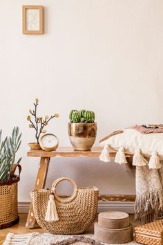 a wooden table topped with baskets filled with succulents next to a white wall