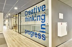 an office with glass walls and wood flooring is pictured in this image, the words creative thinking progress are displayed on the glass wall