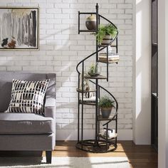 a living room with a spiral metal shelf next to a gray couch and white brick wall