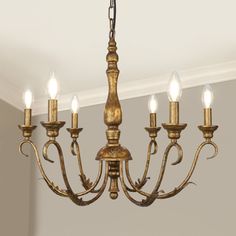 a chandelier with five lit candles hanging from it's center beam in a room