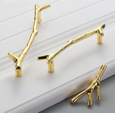 two pairs of gold - plated giraffe hooks on a window sill