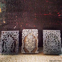 three decorative metal boxes sitting on top of a carpeted floor next to a wall