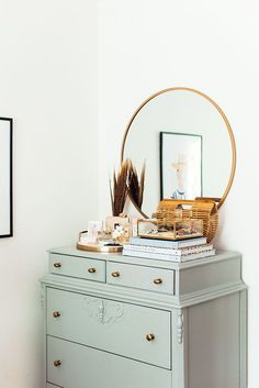 a dresser with a mirror and pictures on the wall next to it, along with other items