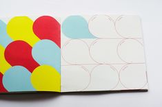 an open book with different colored circles on the front and back cover, sitting on a white surface