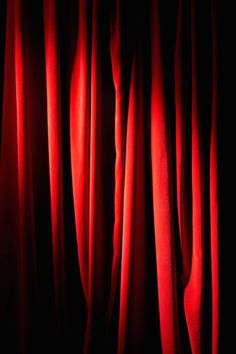 the curtains are red and black in this dark room with only one light on them