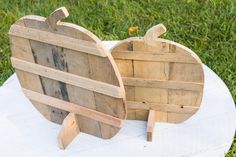 an apple shaped wooden object sitting on top of a white cloth covered table in the grass