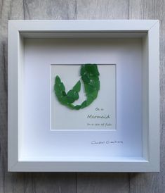 a white frame with a green leaf in it that reads be a mermaid, not a fish