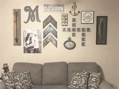 a gray couch sitting in front of a wall covered with pictures and other things on it