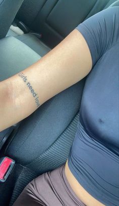 a woman with a tattoo on her arm sitting in the back seat of a car