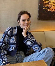 a woman sitting at a table with her hand on her chin and looking to the side