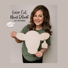 a woman holding up a laser cut wooden cow