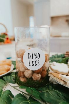 a table topped with lots of food next to a glass jar filled with nuts and cheese