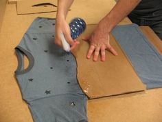 a man is making a t - shirt out of cardboard and glues it with his hands