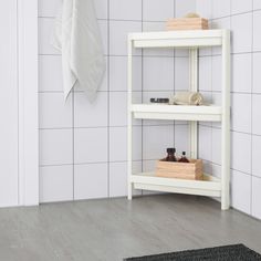 a white shelf in the corner of a bathroom