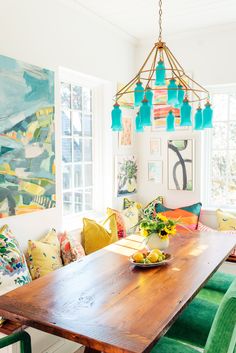 a dining room table with green chairs and colorful artwork on the wall in the background