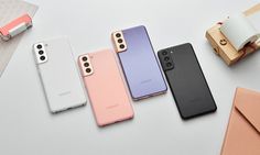 four samsung phones are lined up next to each other on a white surface, one is pink and the other is blue