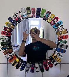 a man taking a selfie in front of a mirror filled with toy cars