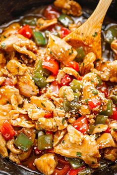 chicken and peppers in a skillet with a wooden spoon