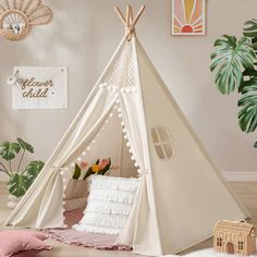 a teepee tent in the corner of a room with pillows and blankets on the floor