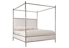 an iron bed frame with white linens and pillows on the bottom, against a white background