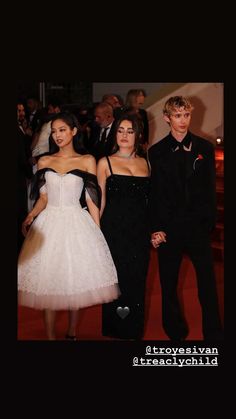 three people standing next to each other in front of a group of people on a red carpet