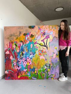 a woman standing next to a large painting