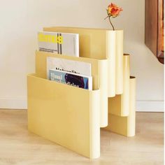 three yellow magazine racks with magazines in them and a flower sticking out of the top