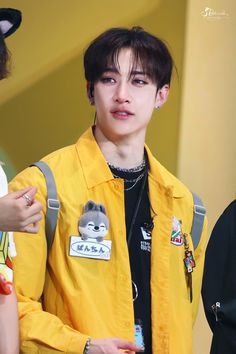 the boy is wearing a yellow jacket with patches on his chest and earrings