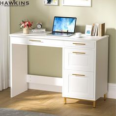 a white desk with a laptop on top of it next to a window and pictures