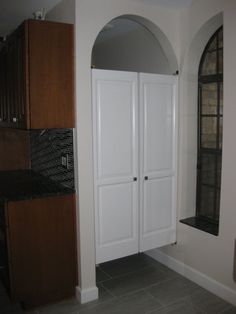 an empty room with two white closets and a black counter top in the corner