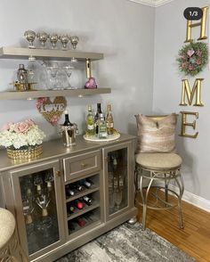 a bar with wine glasses, champagne bottles and vases on the top shelf next to two stools