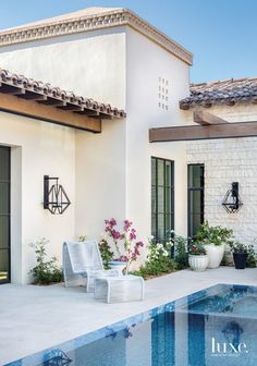 a house with a swimming pool in front of it and flowers growing on the side