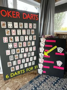 two black boards with white and pink playing cards on them next to each other in front of a window