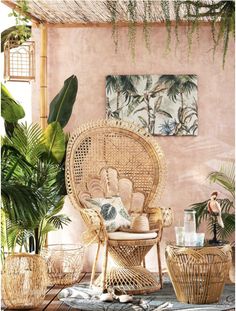 a wicker chair and table with potted plants in front of a pink wall