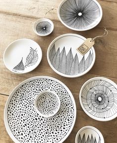 black and white plates with designs on them sitting on a wooden table next to each other