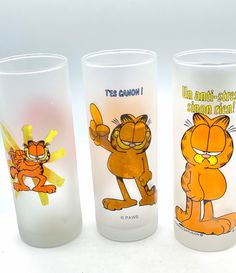 three glass cups with cartoon characters painted on the side and one has an orange cat