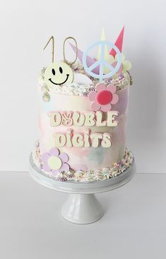 a birthday cake decorated with flowers and peace signs on the top is pink, white, and blue