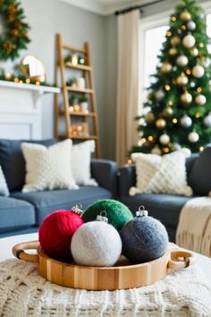 three balls of wool sit on a wooden tray in front of a decorated christmas tree