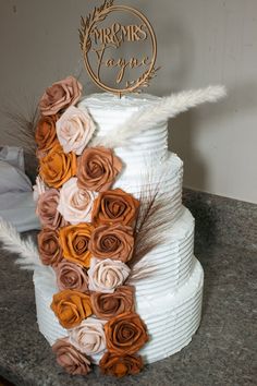 a wedding cake decorated with flowers and feathers