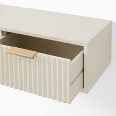 a white cabinet with two drawers and a gold handle on the bottom drawer that is open