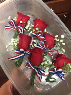 red roses and baby's breath in a clear plastic container with ribbon around the stems